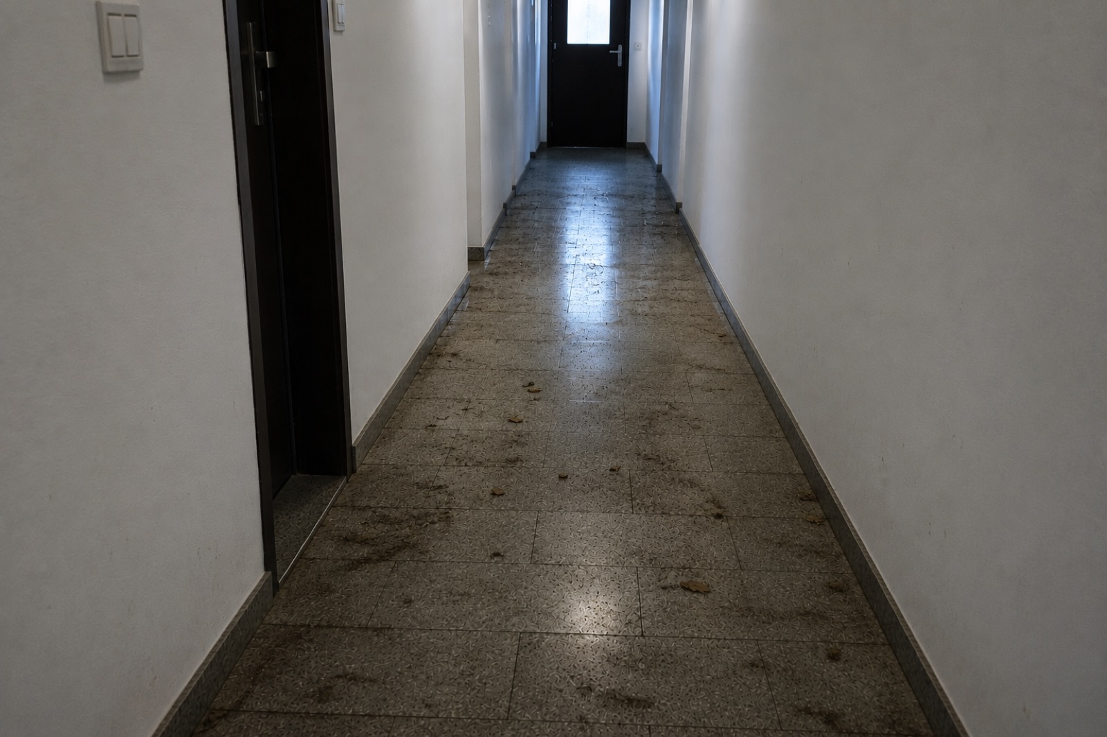 Verschmutzter Hausflur mit Schmutzspuren auf dem Boden vor der Reinigung